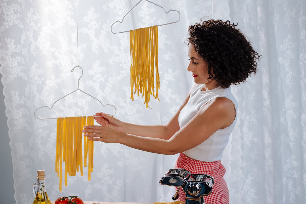 Woman hanging fresh homemade pasta to dry, showcasing Italian cooking methods.