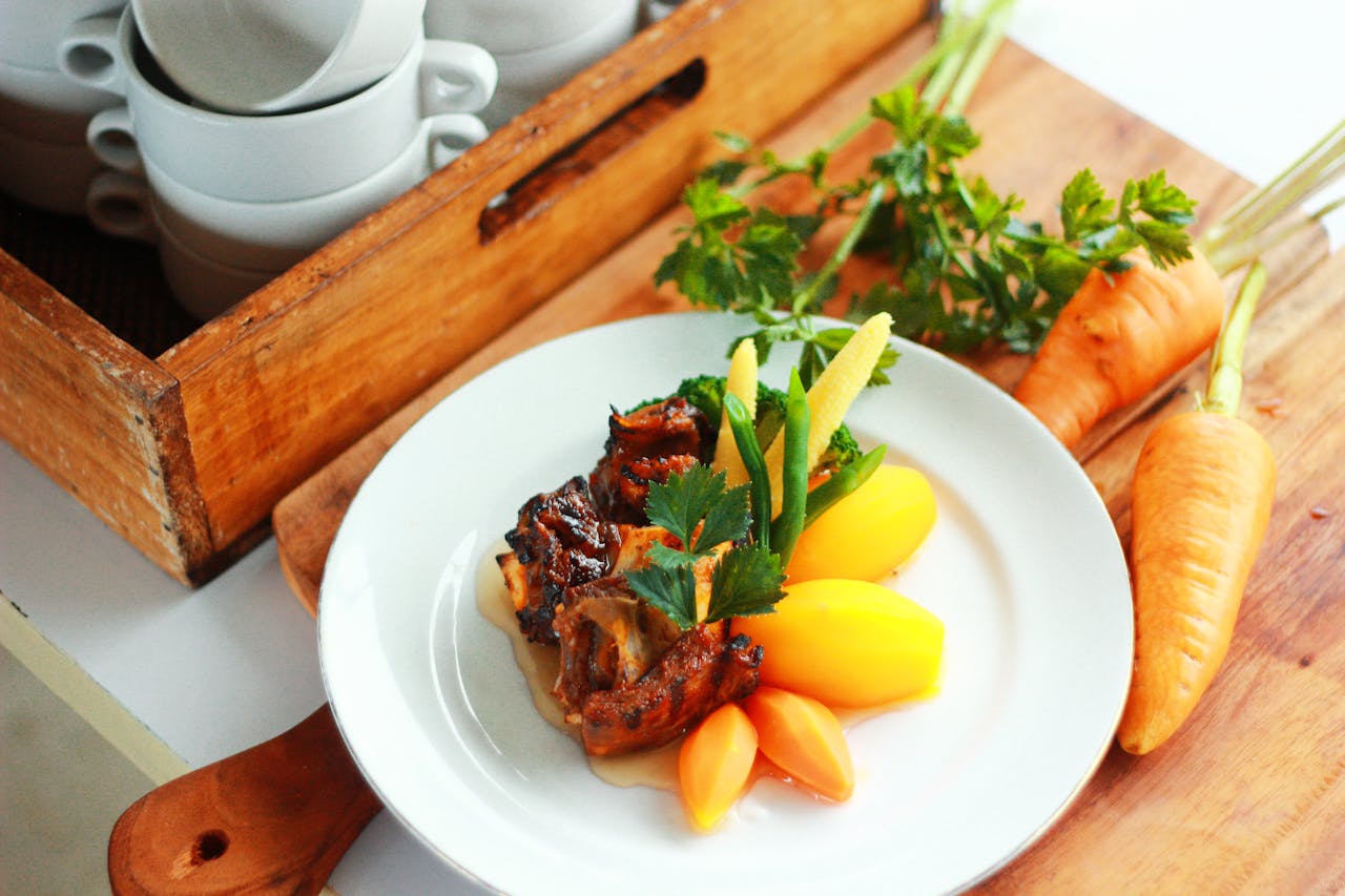 Delicious grilled meat served with carrots and potatoes on a wooden board.