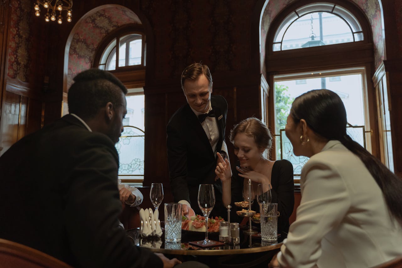 A group of elegantly dressed individuals enjoying a refined dining experience in a luxurious restaurant setting.